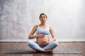 Young pregnant woman doing yoga exercises and meditating at home. Health care, mindfulness, relaxation and wellness