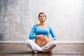 Young pregnant woman doing yoga exercises and meditating at home. Health care, mindfulness, relaxation and wellness