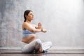 Young pregnant woman doing yoga exercises and meditating at home. Health care, mindfulness, relaxation and wellness