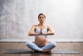 Young pregnant woman doing yoga exercises and meditating at home. Health care, mindfulness, relaxation and wellness