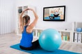 Pregnant Woman Doing Yoga By Watching Television Royalty Free Stock Photo