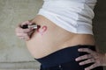 Young pregnant woman drawing a lipstick heart on belly