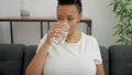 Young pregnant woman drinking glass of water sitting on sofa at home Royalty Free Stock Photo