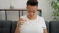 Young pregnant woman drinking glass of water sitting on sofa at home Royalty Free Stock Photo