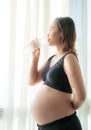 Young pregnant woman drinking water from bottle