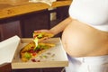 Young pregnant woman eating pizza at the kitchen Royalty Free Stock Photo