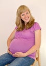 The young pregnant woman embraces hands a stomach on light a background