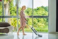 Young pregnant woman enjoys cleaning her house. Easy cleaning with a wireless vacuum cleaner. Pregnant woman cleaning Royalty Free Stock Photo