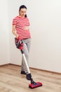 Young pregnant woman enjoys cleaning her house. Easy cleaning with a wireless vacuum cleaner Royalty Free Stock Photo