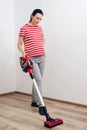 Young pregnant woman enjoys cleaning her house. Easy cleaning with a wireless vacuum cleaner Royalty Free Stock Photo