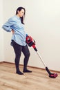Young pregnant woman enjoys cleaning her house. Easy cleaning with a wireless vacuum cleaner Royalty Free Stock Photo