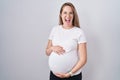 Young pregnant woman expecting a baby, touching pregnant belly smiling and laughing hard out loud because funny crazy joke Royalty Free Stock Photo