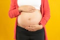 Young pregnant woman expecting a baby. Pregnant woman touching big belly with hands on yellow background. Royalty Free Stock Photo