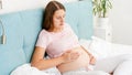 Young pregnant woman feeling hard pain in stomach holding hands on belly while lying in bed at home Royalty Free Stock Photo