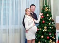 Young pregnant woman and happy father decorating christmas tree