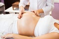 Young pregnant woman having abdominal massage at beauty spa salon. Close-up. Spa treatment Royalty Free Stock Photo