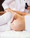 Young pregnant woman having abdominal massage at beauty spa salon. Close-up. Spa treatment Royalty Free Stock Photo