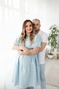 young pregnant woman with her family at home. beautiful family. husband hugging his pregnant wife near a large bright window Royalty Free Stock Photo