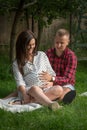 Young pregnant woman and her husband sitting in the garden