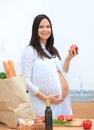 Young pregnant woman holding an Apple,standing in the kitchen Royalty Free Stock Photo