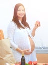 Young pregnant woman holding an Apple,standing in the kitchen Royalty Free Stock Photo