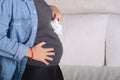 Young pregnant woman holding baby booties on her abdomen. Royalty Free Stock Photo