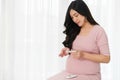 Pregnant woman holding glucose meter and checking blood sugar level by herself at home. gestational diabetes concept Royalty Free Stock Photo