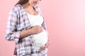 Young pregnant woman holding hands on belly against color background, closeup Royalty Free Stock Photo