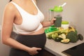 Pregnant woman holding shaker with a green protein cocktail