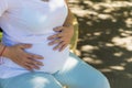 A young pregnant woman holds her hands on her tummy and feels the tremors of her baby