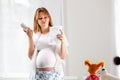 A young pregnant woman holds tablets in her hands and reads the instructions for using the medicine with disdain. Concept of