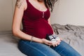 young pregnant woman at home sitting on bed and holding baby shoes Royalty Free Stock Photo