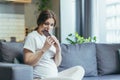 Young pregnant woman at home sitting on the couch eating chocolate Royalty Free Stock Photo