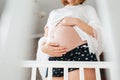 A young pregnant woman hugs her belly. View from the crib, below. Concept of pregnancy and happy motherhood