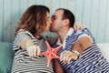 Young pregnant woman with husband on white sofa in blue room. Kissing couple holding a starfish in the hands and dressed Royalty Free Stock Photo