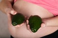 Young pregnant woman keeps two avocados close to her belly Royalty Free Stock Photo