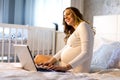 Young pregnant woman with laptop in the bed Royalty Free Stock Photo