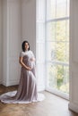 Young pregnant woman in a light classic interior.