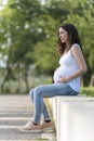 Young pregnant woman looking her belly sitting in the street Royalty Free Stock Photo