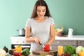 Young pregnant woman making fresh vegetable salad in kitchen Royalty Free Stock Photo