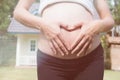 young pregnant woman making heart shape sign on her tummy in fro Royalty Free Stock Photo