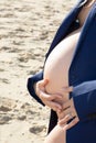 Young pregnant woman in man blue jacket standing on the beach Royalty Free Stock Photo