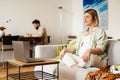 Young pregnant woman meditating and using laptop while sitting on couch Royalty Free Stock Photo