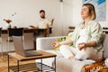 Young pregnant woman meditating and using laptop while sitting on couch Royalty Free Stock Photo