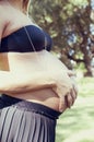 Young pregnant woman at park touching her belly