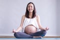 Young pregnant woman practicing yoga while sitting in lotus position Royalty Free Stock Photo