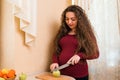 Young pregnant woman preparing fruit salad at home kitchen. Healthy nutrition and diet during pregnancy Royalty Free Stock Photo