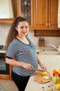 Young pregnant woman preparing fruit salad at home kitchen. Healthy nutrition and diet during pregnancy Royalty Free Stock Photo