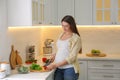 Young pregnant woman preparing vegetable salad at table in kitchen. Healthy eating Royalty Free Stock Photo