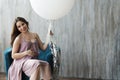 A young pregnant woman in a purple dress sitting on a chair. Royalty Free Stock Photo